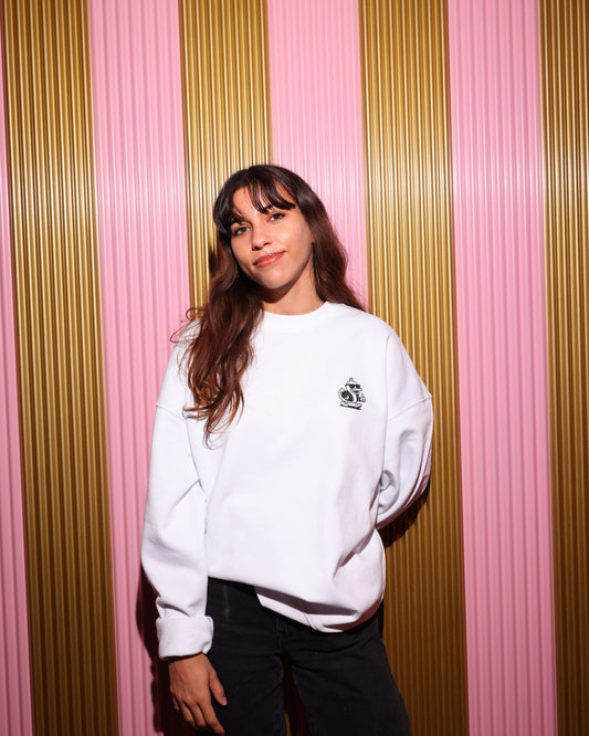 Person wearing a white sweatshirt with a logo against a striped pink and gold background